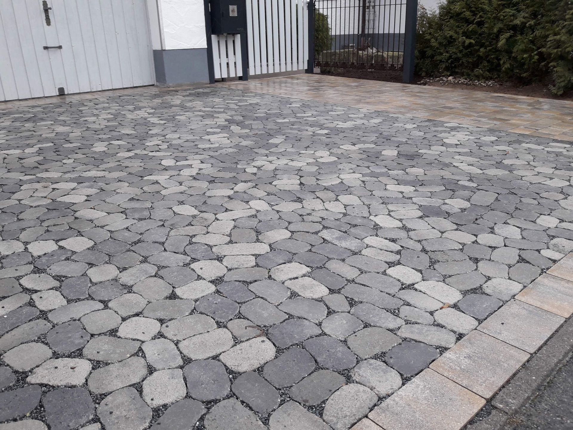 Mauer aus Pflastersteinen vor kleinem Blumenbeet